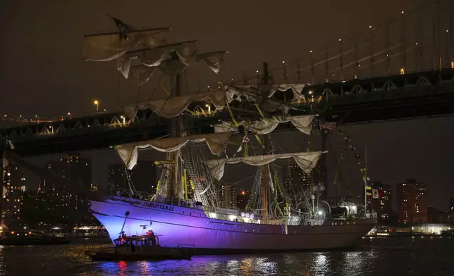 A New York Police Department harbor unit passes in front of the Cuauhtémoc, a masted Mexican Navy training ship as it sits stranded near the Manhattan Bridge after colliding with the Brooklyn Bridge, Saturday, May 17, 2025, in New York. (AP Photo/Yuki Iwamura)