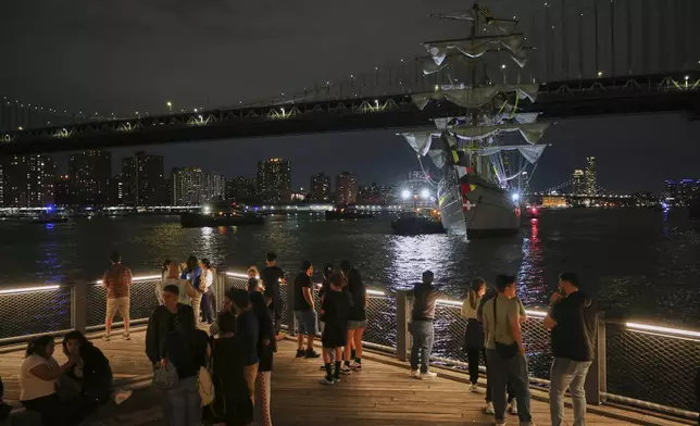 Visitors to Brooklyn Bridge Park look on as a masted Mexican Navy training ship sits stranded near the Manhattan Bridge after colliding with the Brooklyn Bridge, Saturday, May 17, 2025, in New York. (AP Photo/Yuki Iwamura)