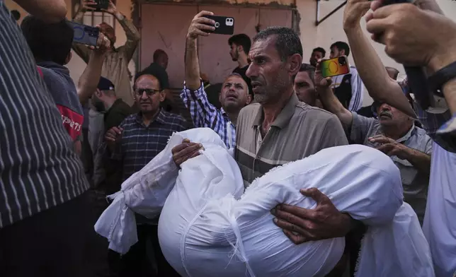 Mohammad Nassar carries the body of his nephew Jana Nassar killed in an Israeli army airstrike on the Gaza Strip, during his funeral at Al-Aqsa Hospital in Deir al-Balah, Gaza, Tuesday, May 20, 2025. (AP Photo/Abdel Kareem Hana)