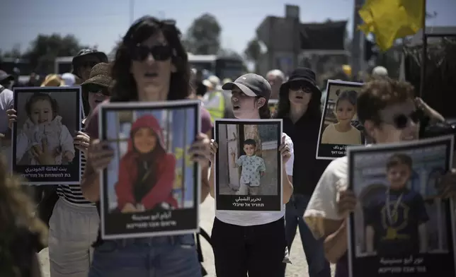 People hold pictures of children killed by Israeli bombardment in the Gaza Strip at a protest demanding the end of the war in an area near the Israeli-Gaza border in Sderot, southern Israel, Friday, May 23, 2025. (AP Photo/Leo Correa)