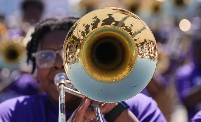The band is reflected in a trombone as the Roots of Music Marching Crusaders parade through the New Orleans Jazz &amp; Heritage Festival in New Orleans, Sunday, May 4, 2025. (AP Photo/Gerald Herbert)