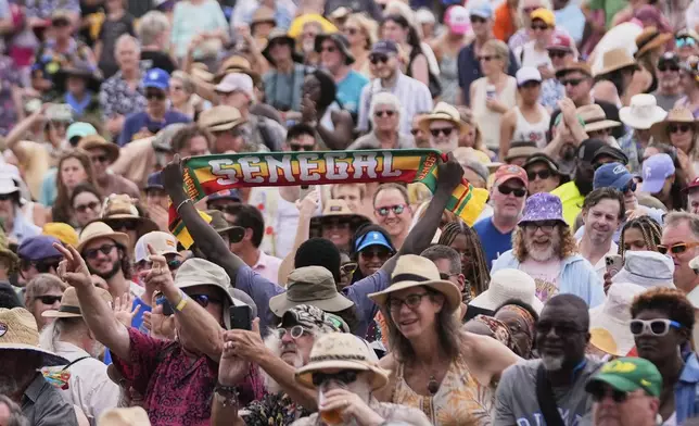 A person in the crow holds up a sign for Senegal as Senegalese artist Youssou N'Dour performs at the New Orleans Jazz &amp; Heritage Festival in New Orleans, Friday, April 25, 2025. (AP Photo/Gerald Herbert)