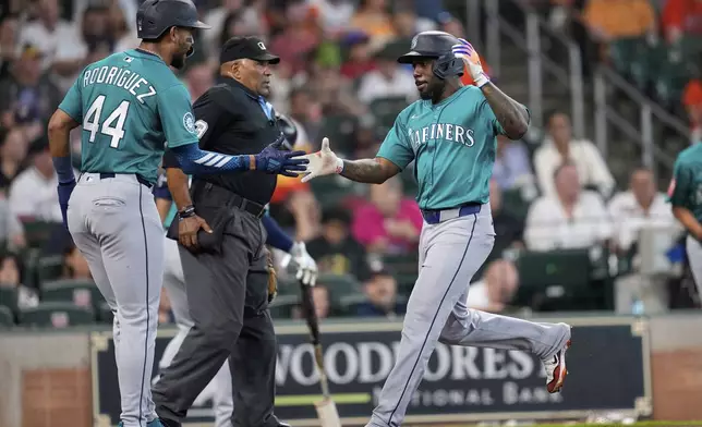 Seattle Mariners' Randy Arozarena, right, celebrates with Julio Rodríguez (44) after both scored on a double by Mitch Garver during the first inning of a baseball game against the Houston Astros Sunday, May 25, 2025, in Houston. (AP Photo/David J. Phillip)