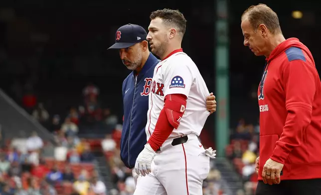 Boston Red Sox's Alex Bregman is led off the field by manager Alex Cora after injuringf himself on a single during the fifth inning against the Baltimore Orioles in the first baseball game of a doubleheader Friday, May 23, 2025, at Fenway Park in Boston. (AP Photo/Winslow Townson)