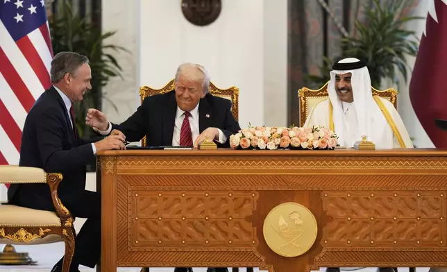 President Donald Trump, center, Qatar's Emir Sheikh Tamim bin Hamad Al Thani and Kelly Ortberg, President and Chief Executive Officer, The Boeing Company, left, share a moment during a signing ceremony at the Amiri Diwan in Doha, Qatar, Wednesday, May 14, 2025. (AP Photo/Alex Brandon)
