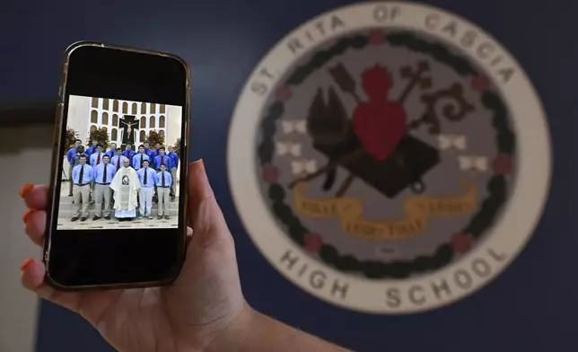 A photo of the new Pope Leo XIV, Chicago native Cardinal Robert Prevost is shown on a phone from when he was a substitute teacher at St. Rita high school Thursday, May 8, 2025, in Chicago. (AP Photo/Paul Beaty)