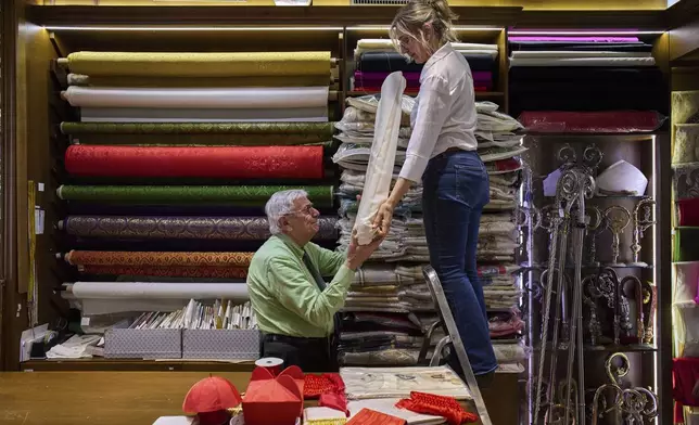 Italian tailor Raniero Mancinelli, 87, and her daughter Laura Mancinelli, 60, prepare the white fabric to create suits, in three different sizes, to be taken to the Vatican in the hope that it might be worn by the new pope, at their shop in Rome, Thursday April 24, 2025. (AP Photo/Bernat Armangue)