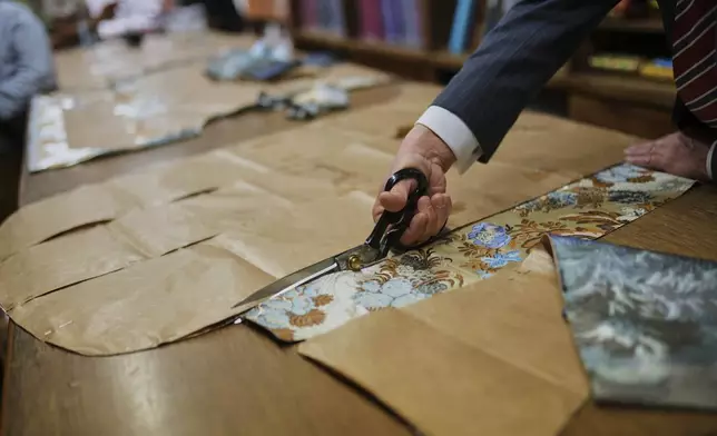 A tailor uses a pattern to cut fabric at the Gammarelli ecclesiastic clothes tailor shop in Rome, Wednesday, April 30, 2025. (AP Photo/Francisco Seco)