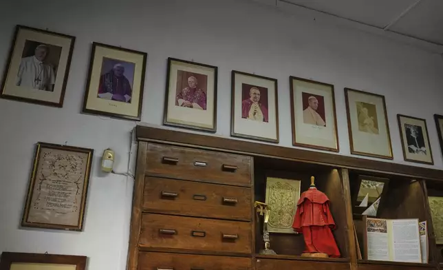 Portraits of late Popes hang at the Gammarelli ecclesiastic clothes tailor shop in Rome, Wednesday, April 30, 2025. (AP Photo/Francisco Seco)