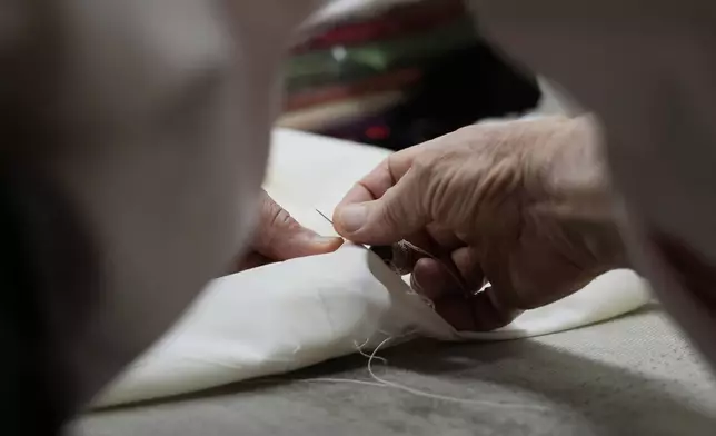 Italian tailor Raniero Mancinelli. who on his own initiative is making outfits for a possible future Pope, works on a pontiff's robe inside his shop in Rome, Wednesday, April 30, 2025. (AP Photo/Gregorio Borgia)