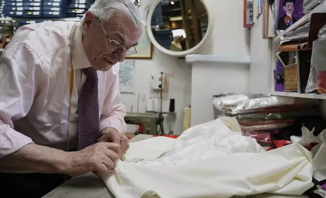 Italian tailor Raniero Mancinelli. who on his own initiative is making outfits for a possible future Pope, works on a pontiff's robe inside his shop in Rome, Wednesday, April 30, 2025. (AP Photo/Gregorio Borgia)