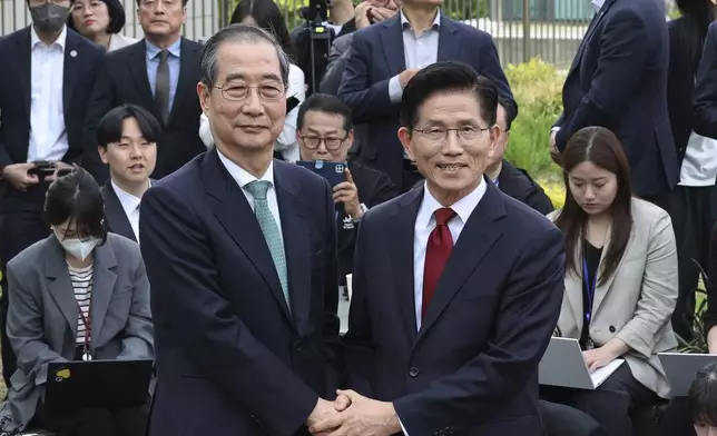 South Korea's People Power Party's presidential election candidate Kim Moon Soo, right, and independent preliminary presidential election candidate Han Duck-soo pose for a photo during a meeting in Seoul, South Korea, Thursday, May 8, 2025. (Yonhap via AP)
