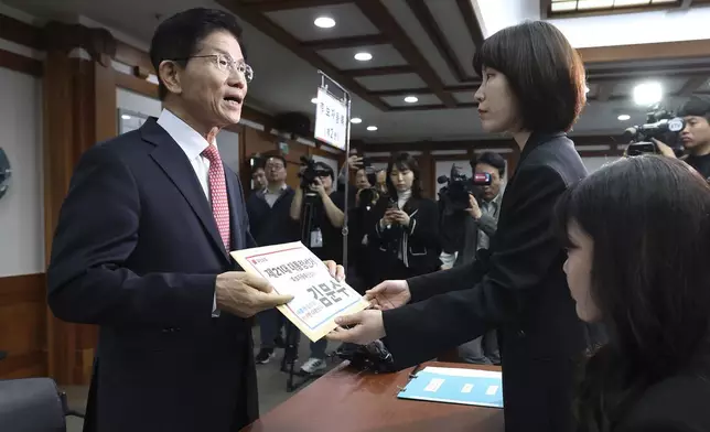 South Korea's People Power Party's presidential election candidate Kim Moon Soo, left, submits documents to register as a candidate to run in the June 3 presidential election, at the National Election Commission, Gwacheon, South Korea, Sunday, May 11, 2025. The letter read "The 21st Presidential election candidate registration application, Kim Moon Soo." (Yonhap via AP)