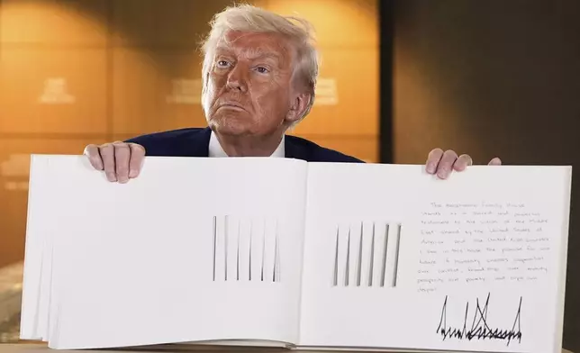 President Donald Trump shows the guest book after touring the Abrahamic Family House, Friday, May 16, 2025, in Abu Dhabi, United Arab Emirates. (AP Photo/Alex Brandon)