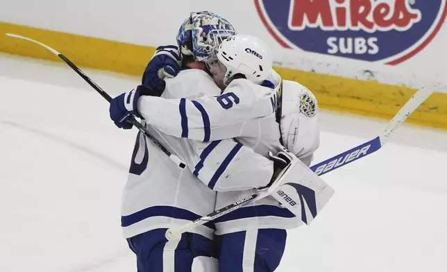 Toronto Maple Leafs goaltender Joseph Woll, left, is hugged by right wing Mitch Marner (16) after the Maple Leafs defeated the Florida Panthers in Game 6 of a second-round NHL hockey playoff series, Friday, May 16, 2025, in Sunrise, Fla. (AP Photo/Lynne Sladky)