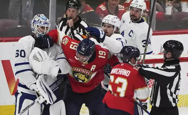 Florida Panthers left wing Matthew Tkachuk (19) and center Brad Marchand (63) scuffles with Toronto Maple Leafs goaltender Joseph Woll (60) and defenseman Simon Benoit, center, right, after the Maple Leafs won Game 6 of a second-round NHL hockey playoff series, Friday, May 16, 2025, in Sunrise, Fla. (AP Photo/Lynne Sladky)