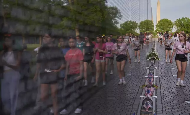 Students are reflected in the wall of names as they visit the Vietnam Veterans Memorial on the 50th Anniversary of the fall of Saigon, Wednesday, April 30, 2025, in Washington. (AP Photo/Jacquelyn Martin)