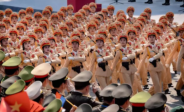 Vietnamese female police officers are saluted by military leaders as the march passes the grand stand during a parade celebrating the 50th anniversary of the end of the Vietnam War on Wednesday, April 30, 2025, in Ho Chi Minh City, Vietnam. (AP Photo/Richard Vogel)