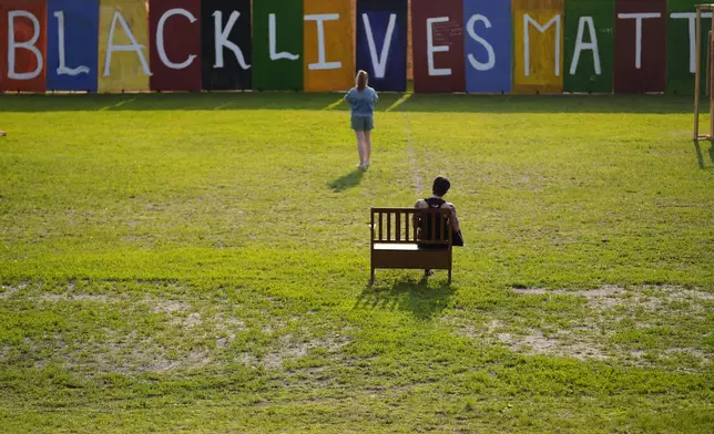 People visit a Black Lives Matter painting in a park near George Floyd Square on the five-year anniversary of Floyd's death, Sunday, May 25, 2025, in Minneapolis. (AP Photo/Abbie Parr)