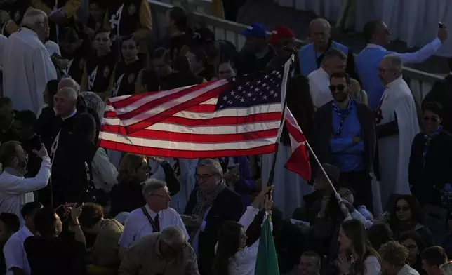 A woman waves a flag from the United States ahead of Pope Leo XIV's formal inauguration of his pontificate with a Mass in St. Peter's Square attended by heads of state, royalty and ordinary faithful, Sunday, May 18, 2025. (AP Photo/Gregorio Borgia)