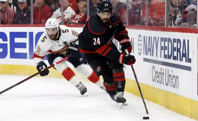 Carolina Hurricanes' Seth Jarvis (24) carries the puck in front of Florida Panthers' Aaron Ekblad (5) during the second period of Game 2 of the NHL hockey Stanley Cup Eastern Conference finals in Raleigh, N.C., Thursday, May 22, 2025. (AP Photo/Karl DeBlaker)