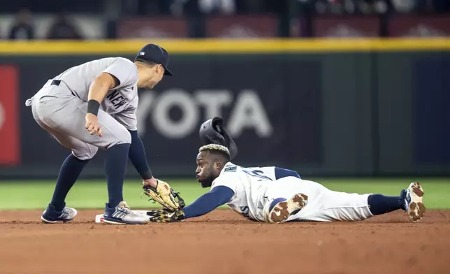 Seattle Mariners' Randy Arozarena steals second base as New York Yankees shortstop Anthony Volpe is unable to hold on to a throw during the fourth inning of a baseball game, Wednesday, May 14, 2025, in Seattle. (AP Photo/Stephen Brashear)