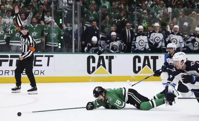 Dallas Stars center Sam Steel (18) is tripped by Winnipeg Jets' Mark Scheifele, right rear, on an attack in the third period of Game 6 of a second-round NHL hockey playoff series in Dallas, Saturday, May 17, 2025. (AP Photo/Gareth Patterson)