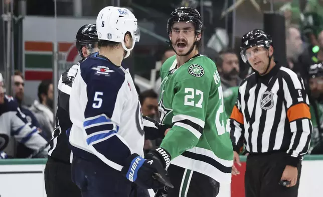 Dallas Stars' Mason Marchment (27) and Winnipeg Jets' Luke Schenn (5) exchange words as officials look on in the second period of Game 6 of a second-round NHL hockey playoff series in Dallas, Saturday, May 17, 2025. (AP Photo/Gareth Patterson)