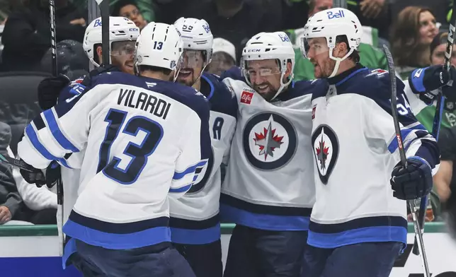 Winnipeg Jets' Gabriel Vilardi (13), Kyle Connor, left rear, Mark Scheifele, center rear, Neal Pionk (4) and Dylan Samberg, right, celebrate after Scheifele scored against the Dallas Stars in the second period of Game 6 of a second-round NHL hockey playoff series in Dallas, Saturday, May 17, 2025. (AP Photo/Gareth Patterson)