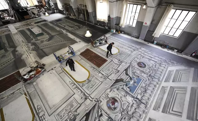 Set designers work on a stage canvas in the "Teatro dell' Opera" opera house warehouse, in Rome, Thursday, April 10, 2025. (AP Photo/Andrew Medichini)