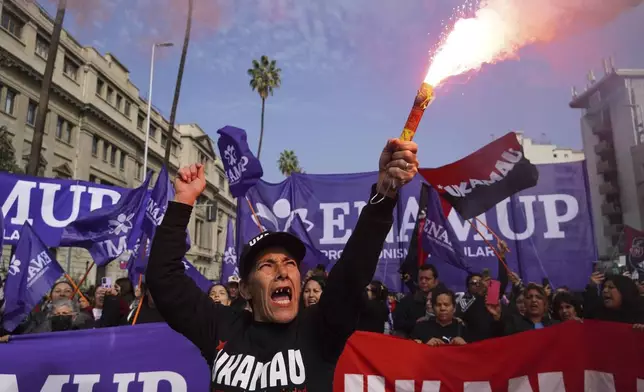 A protester holds a flare during an International Workers' Day march marking May Day in Santiago, Chile, Thursday, May 1, 2025. (AP Photo/Matias Basualdo)