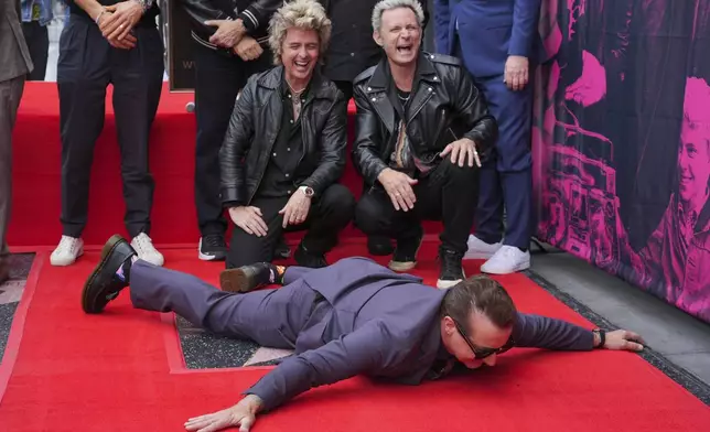 Tre Cool, from left, Billie Joe Armstrong, and Mike Dirnt of Green Day pose with their new star during a ceremony on the Hollywood Walk of Fame on Thursday, May 1, 2025, in Los Angeles. (AP Photo/Chris Pizzello)
