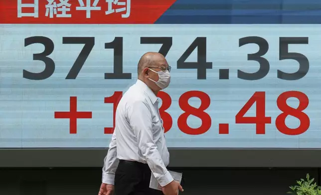 A person walks in front of an electronic stock board showing Japan's Nikkei index at a securities firm Friday, May 23, 2025, in Tokyo. (AP Photo/Eugene Hoshiko)