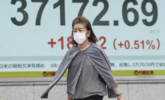 A person walks in front of an electronic stock board showing Japan's Nikkei index at a securities firm Friday, May 23, 2025, in Tokyo. (AP Photo/Eugene Hoshiko)