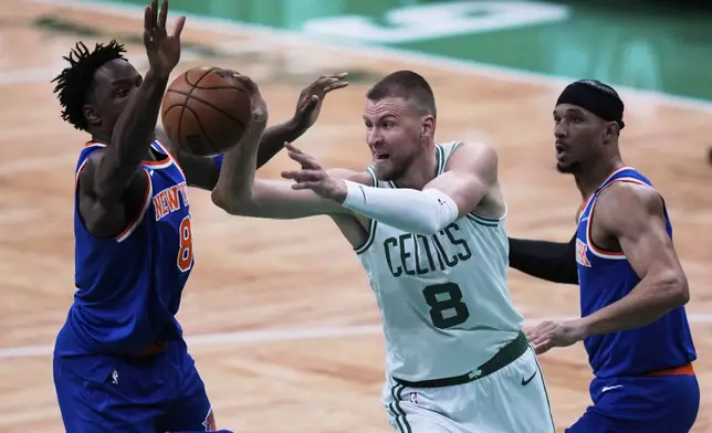 Boston Celtics center Kristaps Porzingis (8) passes the ball while pressured by the New York Knicks during the first half of Game 1 of an NBA basketball second-round playoff series Monday, May 5, 2025, in Boston. (AP Photo/Charles Krupa)