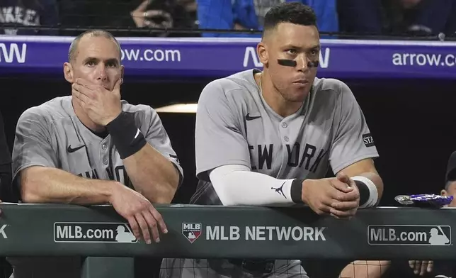 New York Yankees' Paul Goldschmidt, left, and Aaron Judge, right, lean over the dugout rail to watch the ninth inning of a baseball game against the Colorado Rockies, Friday, May 23, 2025, in Denver. (AP Photo/David Zalubowski)