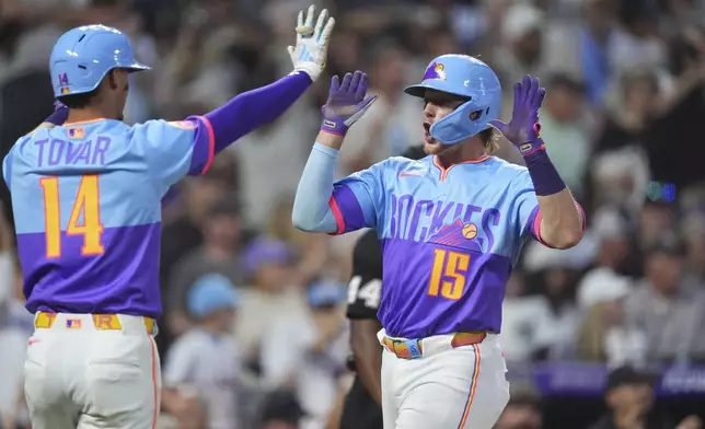 Colorado Rockies' Ezequiel Tovar, left, celebrates with Hunter Goodman, right, after they scored on a double hit by Ryan McMahon off New York Yankees relief pitcher Tim Hill in the fifth inning of a baseball game Friday, May 23, 2025, in Denver. (AP Photo/David Zalubowski)