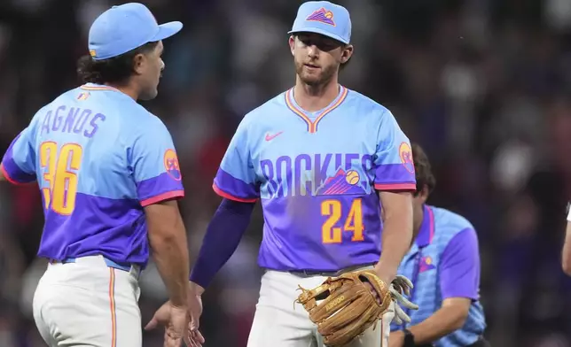 Colorado Rockies relief pitcher Zach Agnos, left, congratulates third baseman Ryan McMahon (24) after a baseball game against the New York Yankees, Friday, May 23, 2025, in Denver. (AP Photo/David Zalubowski)
