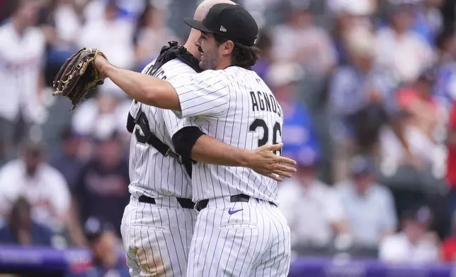 Colorado Rockies catcher Jacob Stallings, left, hugs relief pitcher Zach Agnos after he closed out the Atlanta Braves to end a baseball game, Wednesday, April 30, 2025, in Denver. (AP Photo/David Zalubowski)