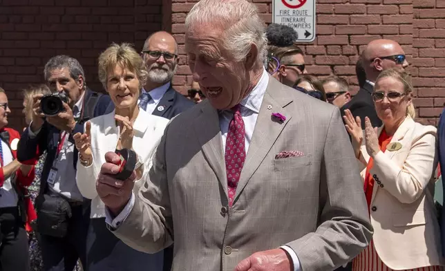 King Charles looks at the puck after participating in a ceremonial puck drop during a visit to Lansdowne Park in Ottawa, Canada, on Monday, May 26, 2025. (Christinne Muschi/The Canadian Press via AP)