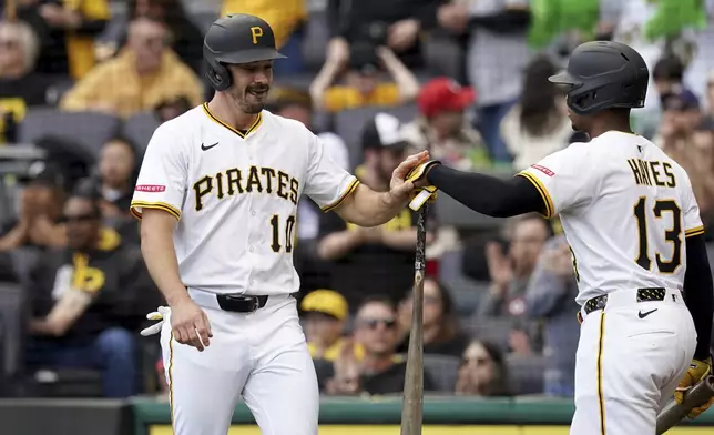 Pittsburgh Pirates' Bryan Reynolds, left, is greeted by Ke'Bryan Hayes, right, after scoring during the first inning of a baseball game against the Milwaukee Brewers, Saturday, May 24, 2025, in Pittsburgh. (AP Photo/Matt Freed)