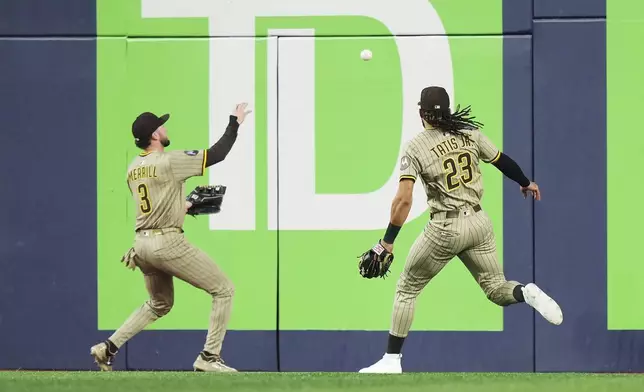 San Diego Padres outfielders Jackson Merrill (3) and Fernando Tatis Jr. (23) field a two-run double off the bat of Toronto Blue Jays' Jonatan Clase during the seventh inning of a baseball game in Toronto on Wednesday, May 21, 2025. (Nathan Denette/The Canadian Press via AP)