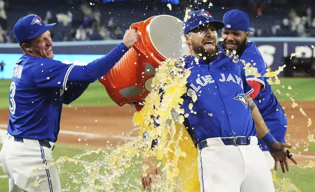 Toronto Blue Jays' Nathan Lukes, center, is doused by Myles Straw, left, and Vladimir Guerrero Jr. after defeating the San Diego Padres in a baseball game in Toronto on Wednesday, May 21, 2025. (Nathan Denette/The Canadian Press via AP)