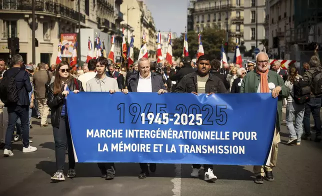 People walk with a banner reading "Inter-generation march for memory and transmission" before the commemoration of the 80th anniversary of the return of the deportees, in Paris, France, Sunday, April 27, 2025. (AP Photo/Thomas Padilla)