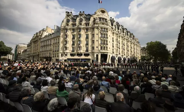 People attend a commemorative ceremony to mark the 80th anniversary of the return of the deportees in front of the Hotel Lutetia, in background, in Paris, France, Sunday, April 27, 2025. (AP Photo/Thomas Padilla)