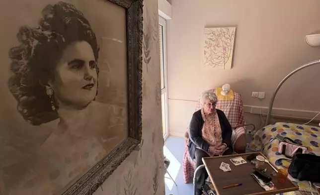 Genevieve Perrier, 99, a civilian under Nazi occupation, answers the Associated Press, with a portrait of her when she was 20 in 1945, on Tuesday April 29 2025 in Precy sous Thil, Burgundy, France. (AP Photo/Nicolas Garriga)