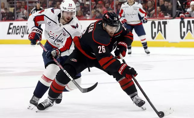 Carolina Hurricanes' Sean Walker (26) controls the puck in front of Washington Capitals' Connor McMichael (24) during the first period of Game 4 of a second-round NHL hockey playoff series in Raleigh, N.C., Monday, May 12, 2025. (AP Photo/Karl DeBlaker)