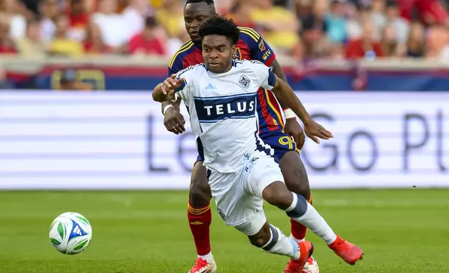 Vancouver Whitecaps midfielder Ralph Priso, front, and Real Salt Lake striker William Agada, back, battle for the ball during an MLS soccer match Saturday, May 24, 2025, in Sandy, Utah. (AP Photo/Tyler Tate)