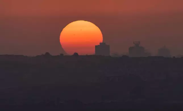 Destroyed buildings in the Gaza Strip are silhouetted in front of the setting sun in southern Israel, Thursday, May 29, 2025. (AP Photo/Ohad Zwigenberg)