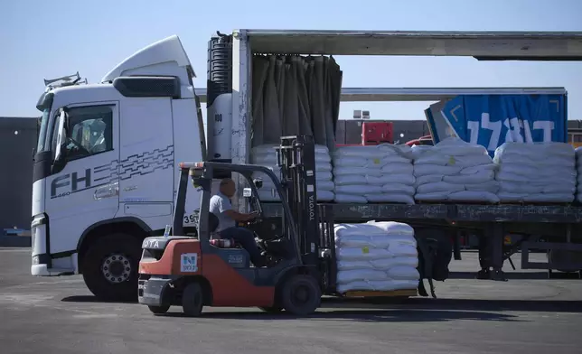 A worker unloads cargo from a truck carrying humanitarian aid for the Gaza Strip at the offload area of the Kerem Shalom border crossing between Israel and Gaza, southern Israel, Thursday, May 29, 2025. (AP Photo/Ohad Zwigenberg)